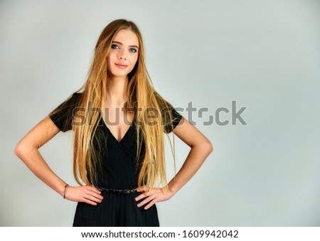 The concept of fashion and style. Portrait of a pretty blonde girl with long hair and great makeup on a white background. The model stands in different poses in front of the camera.