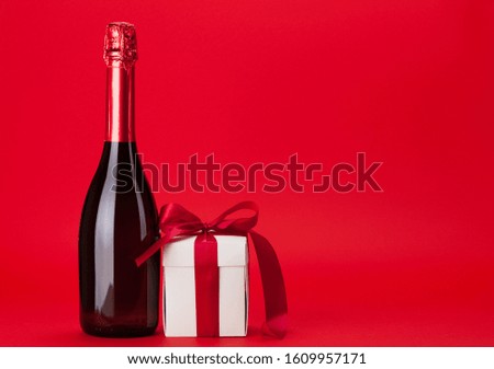 Valentines day gift box and champagne bottle over red background with copy space for your greetings