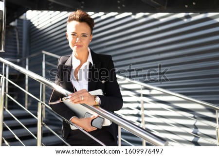 successful boss woman stands on stairs of financial business center