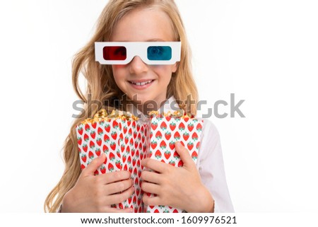 A little girl with makeup and long blonde hair, 3d glasses looks film or cartoon with popcorn isolated on white background