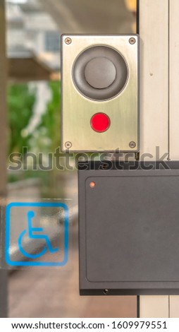 Vertical Glass door of a modern building with security key card reader and handicap sign