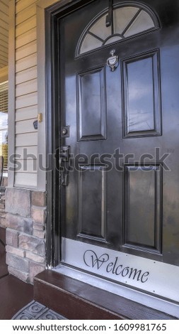 Vertical frame Front door of house with glass panes and porch with chairs railings and columns