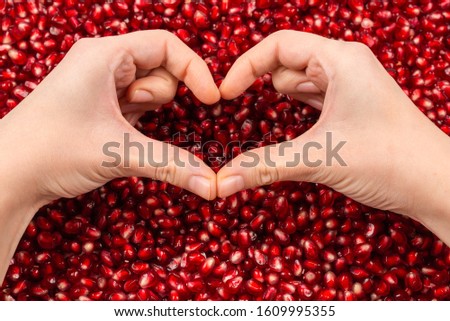 Heart symbol. Pomegranate seeds in woman hand.