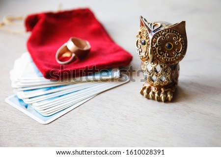 Fortune telling, Brown magic owl and Tarot card deck with red velvet bag on old wooden table. Selective focus. Copy space  