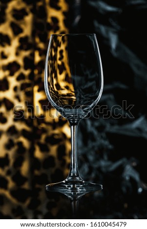 empty transparent glass wine glass stands on the glass on a yellow spotted background close-up. Right black background
