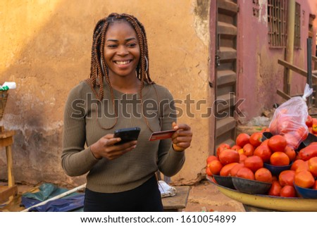 Young beautiful black market woman making an online payment with her card on her mobile phone