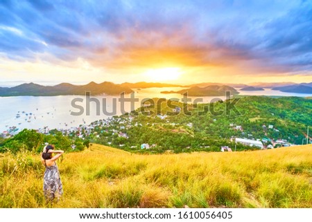 Brunette Woman looking at view from Mount Tapyas on Coron Island - North Palawan, Philippines. Looking over Coron Town and Bay at Sunset.