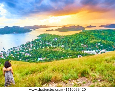 Brunette Woman looking at view from Mount Tapyas on Coron Island - North Palawan, Philippines. Looking over Coron Town and Bay at Sunset.