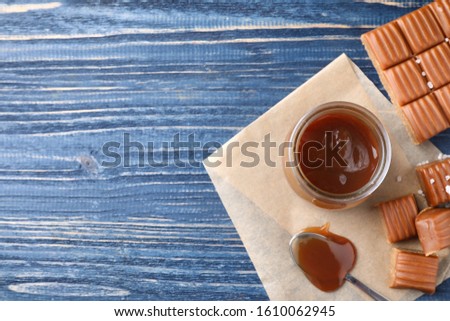 Salted caramel on blue wooden table, flat lay. Space for text