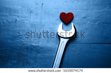 Wrench and red heart on a textured blue background.