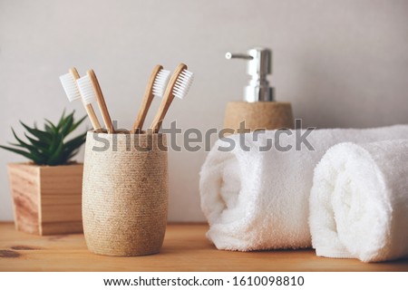 Four bamboo toothbrushes in a cup and white towels Royalty-Free Stock Photo #1610098810