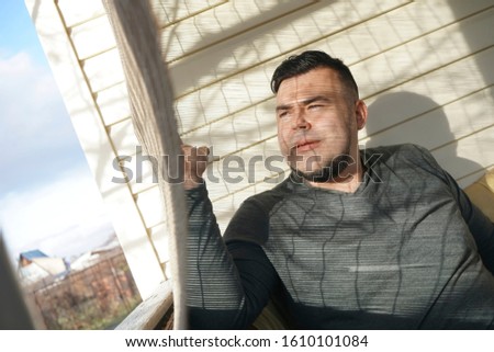 Handsome man near window with Venetian blinds. Space for text. Shadow of a man and blinds on the wall. horizontal  view.