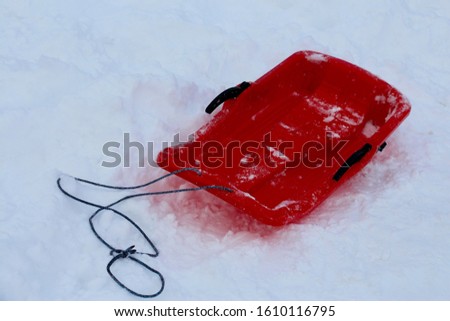 A red plastic snow sled toboggan on the snow in  the mountain