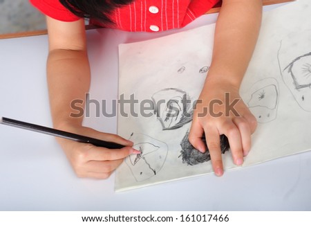 children hand with pencil draws and sketches many human faces. Education Concept.