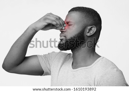 Young afro man having issues with vision, rubbing his nose and eyes, black and white Royalty-Free Stock Photo #1610193892