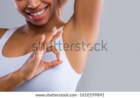 Cropped of black woman looking at shaved armpit, showing okay gesture over grey background Royalty-Free Stock Photo #1610199841