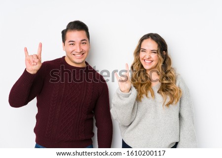 Young couple posing in a white background showing a horns gesture as a revolution concept.