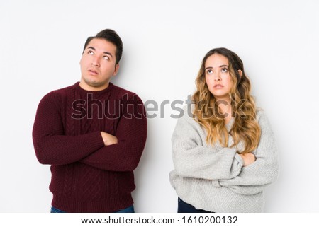 Young couple posing in a white background tired of a repetitive task.