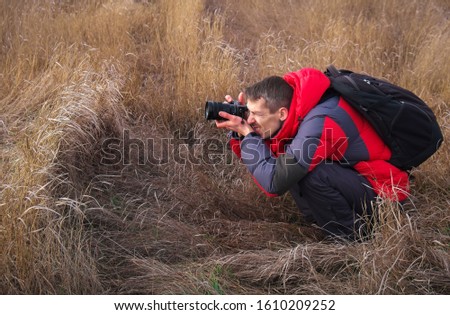 An experienced photographer takes pictures in nature. A professional video maker shoots scenes.