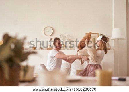 Pair in love laughing and playing on bed. Man and woman fight pillows. Young happy couple beat the pillows on the bed in a bedroom at home.