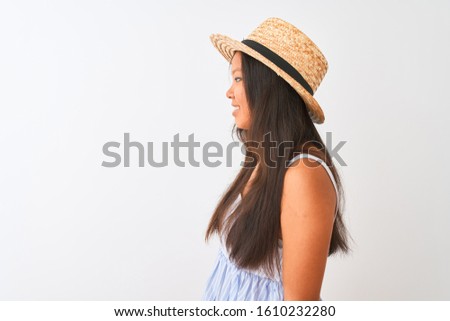 Young chinese woman wearing striped dress and hat standing over isolated white background looking to side, relax profile pose with natural face with confident smile.
