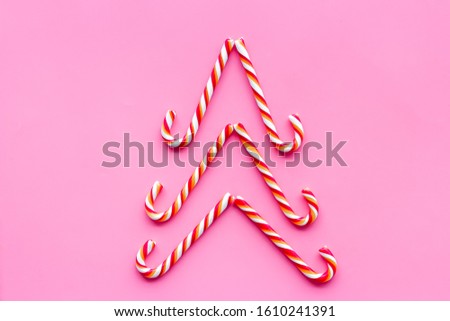 New Year tree lined with Christmas candy cane on pink backgound top-down copy space