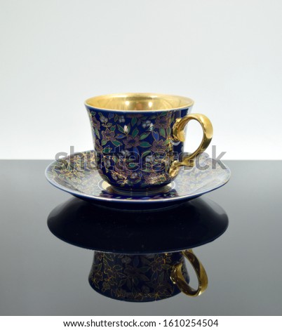 The teacup is placed on a saucer ceramic in gold. Placed on a black background with reflection Decorate the house in the showcase