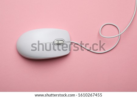 Wired computer mouse on pink background, top view