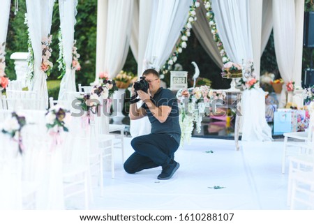 photographer making photos of wedding decoration at white arbor
