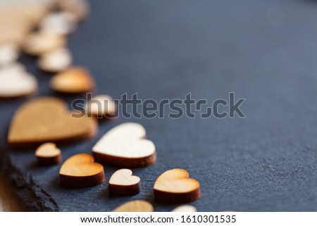 Heart shape made of natural wood. Beautiful heart shaped wooden little hearts on black background. Concept with wooden hearts for Valentine background and theme of love. Place for text. Close up.