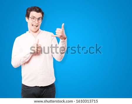 Amazed young man making a gesture of calling with the hand