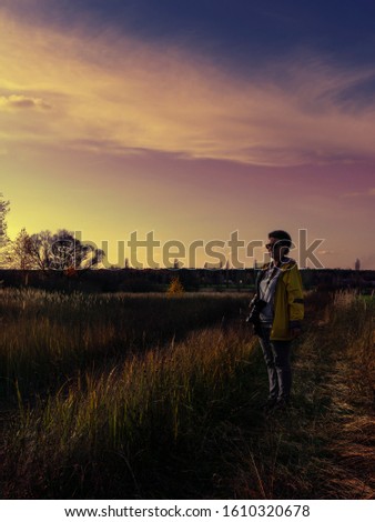 Woman photographer chooses a place to shoot a beautiful landscape. Autumn, sunset.