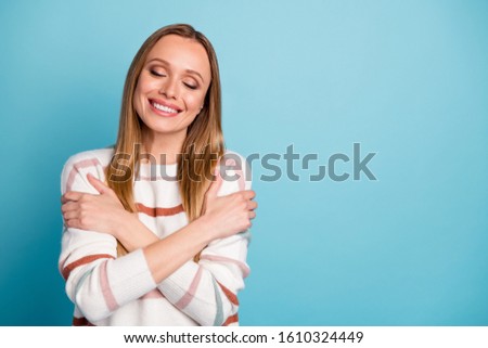 Photo of cheerful positive pretty nice charming woman smile toothy near empty space hugging herself isolated over pastel color background