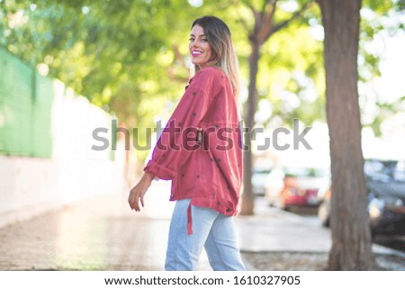 Young beautiful woman wearing red jacket smiling happy and confident. Standing with smile on face at the town street