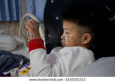 asian chinese boy playing smartphone on bed, kid use phone and play game, addicted game and cartoon, 
