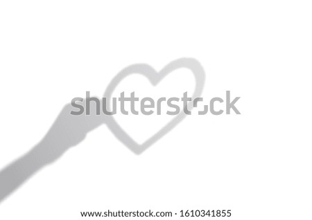 Concept modern abstract background of shadow heart frame in hand on a white wall. White and Black for overlaying a valentine photo or mockup