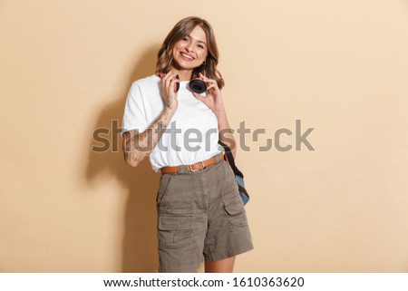 Image of young teen girl wearing headphones smiling and walking isolated over beige background