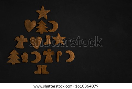 Christmas ginger cookies in the shape of Christmas trees, stars, angels and hearts on a dark concrete background
