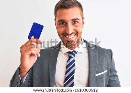 Young handsome business man holding credit card over isolated background with a happy face standing and smiling with a confident smile showing teeth