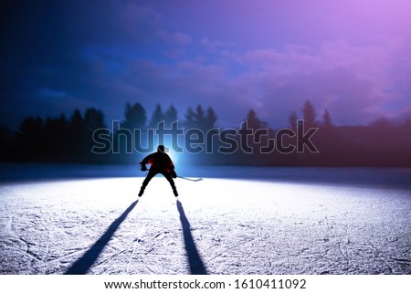 Young hockey player silhouette on the night ice