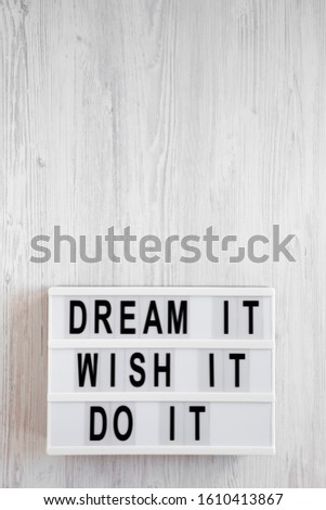 'Dream it, wish it, do it' words on a lightbox on a white wooden surface, top view. Overhead, from above, flat lay. Copy space.