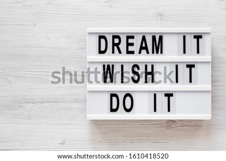 'Dream it, wish it, do it' words on a modern board on a white wooden background, top view. Overhead, from above, flat lay. Copy space.