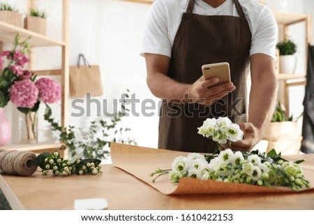 Florist taking picture of beautiful flowers in workshop, closeup