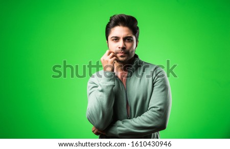 Handsome Indian / asian depressed man standing isolated over green background looking stressed and nervous having  Anxiety problem. selective focus