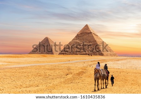 Pyramids of Giza and the tourists on a camel, Egypt Royalty-Free Stock Photo #1610435836