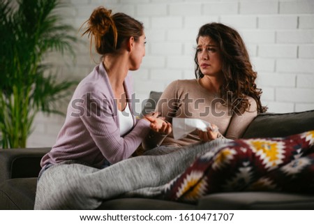 Girlfriend giving comfort to her best friend at home on sofa. Royalty-Free Stock Photo #1610471707