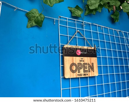 open sign wooden broad through the blue wall and plant. Business service and food concept, the second floor, vintage yet modern tone bold color style