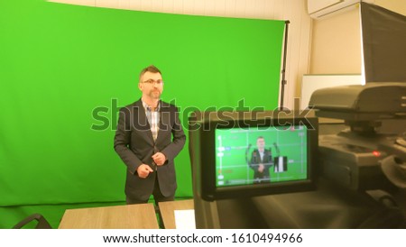 A blogger is recording a video on a green background. Record a video blog on a chroma key background. The camcorder is recording a blogger.