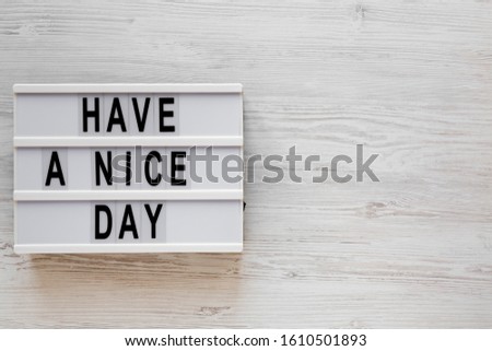 'Have a nice day' words on a lightbox on a white wooden surface, top view. Overhead, from above, flat lay. Copy space.