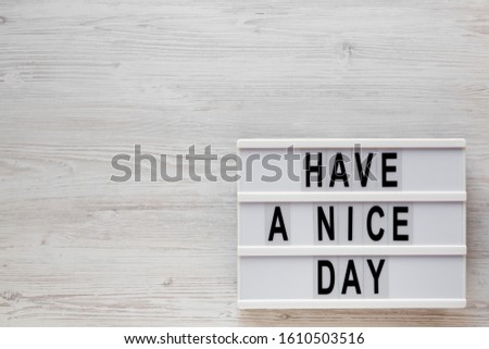 'Have a nice day' words on a lightbox on a white wooden surface, top view. Overhead, from above, flat lay. Copy space.